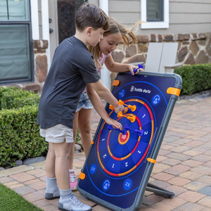 Two children playing with a magnetic dart board outdoors.